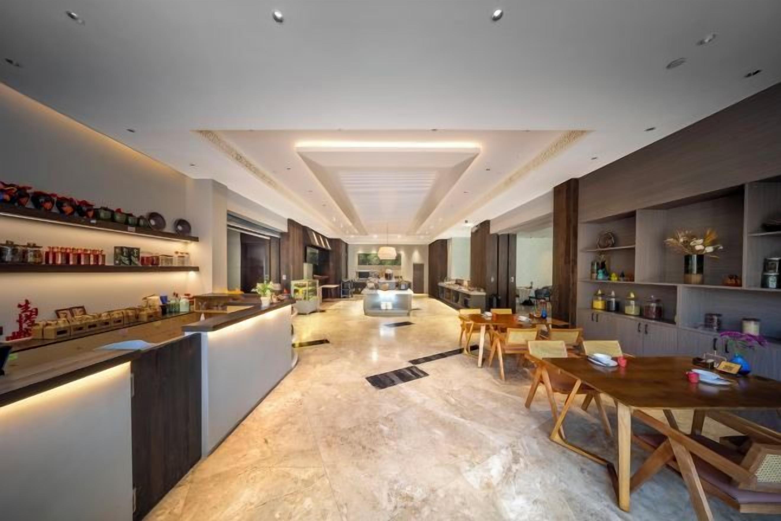 A modern kitchen with a central island, a dining area with wooden chairs, and a bar area with shelves.