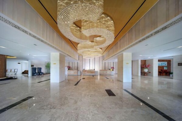 A spacious lobby with a large, circular chandelier and a marble floor.