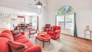 A spacious living room with a red sofa set, a wooden coffee table, and a dining area with a red chair. - Spacious San Antonio Home: Google Fiber, Game Room (San Antonio)