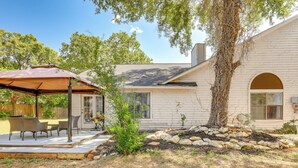 A house with a covered patio, outdoor seating, and a stone retaining wall. - Spacious San Antonio Home: Google Fiber, Game Room (San Antonio)