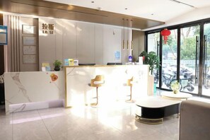 A modern reception area with a marble counter, two bar stools, and a seating area with a round table. - Las Gaming Hotel (Ruian Wansong Branch) (Rui'an)