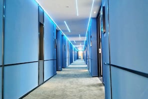 A long, narrow hallway with blue walls and a patterned floor, leading to a bright area at the end. - Las Gaming Hotel (Ruian Wansong Branch) (Rui'an)