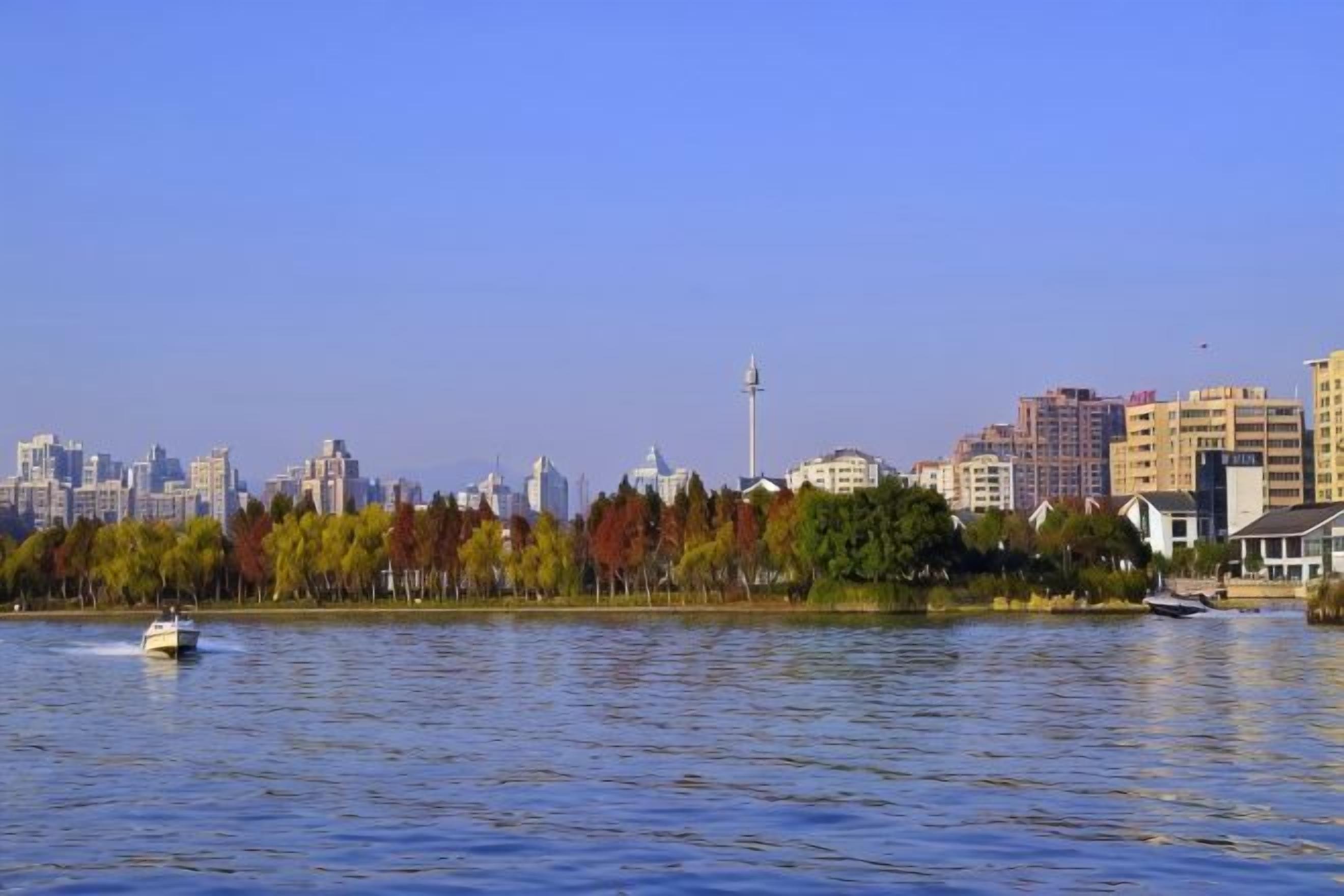 A body of water with a city skyline in the background, including a tower and various buildings.