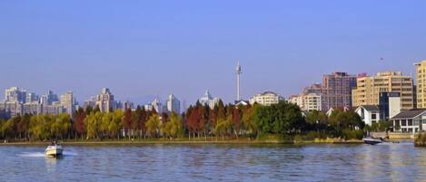 A body of water with a city skyline in the background, including a tower and various buildings.