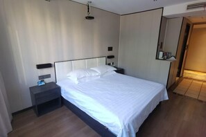 Ένα δωμάτιο ξενοδοχείου με ένα κρεβάτι, ένα κομοδίνο, φωτιστικά τοποθετημένα στον τοίχο και έναν καθρέφτη.