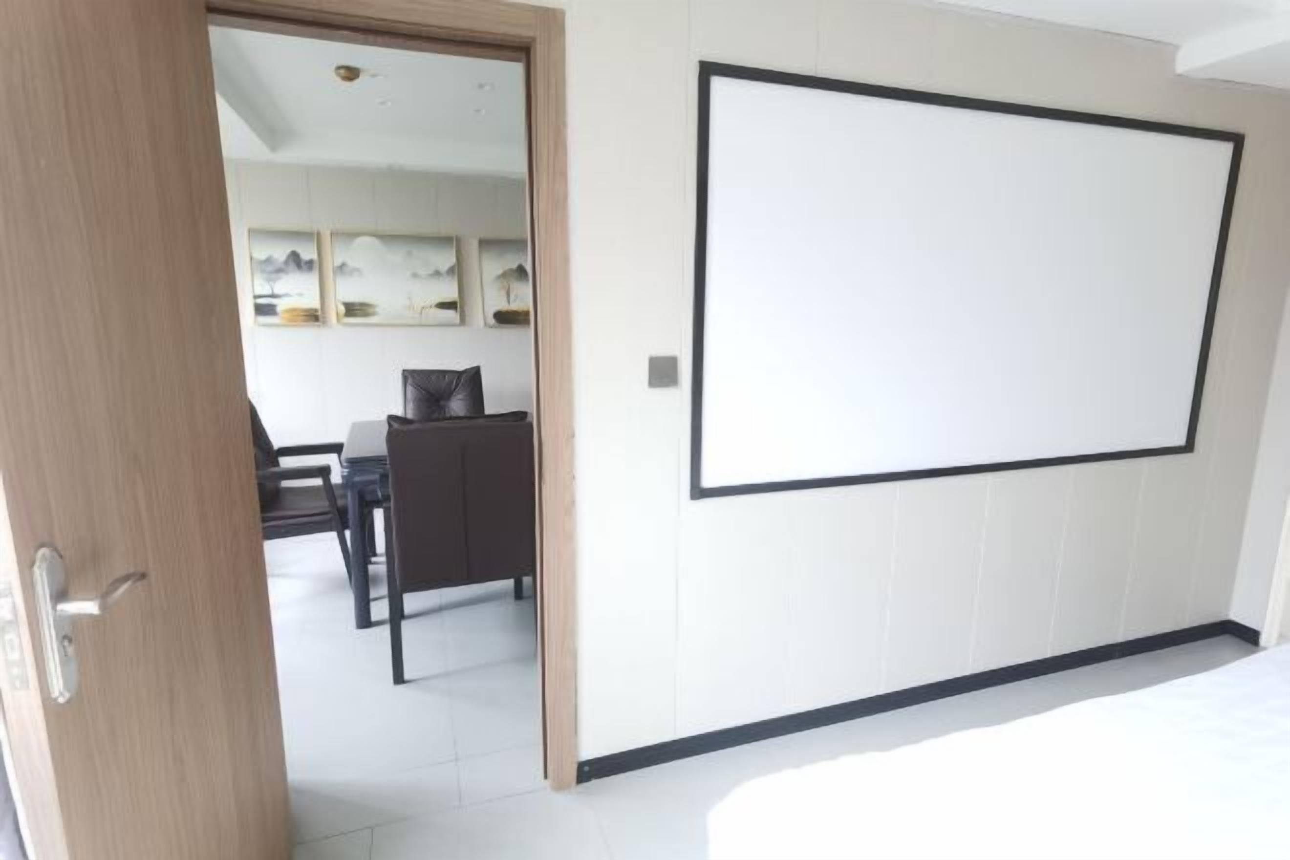 A room with a large bed, a wooden door, and a dining area with a table and chairs.