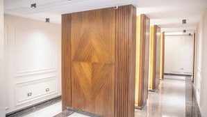 A hallway with a wooden panel divider, marble flooring, and recessed lighting. - Gaia Pyramids View INN (Giza)