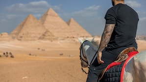 A person riding a horse with a saddle, in front of the pyramids. - Gaia Pyramids View INN (Giza)
