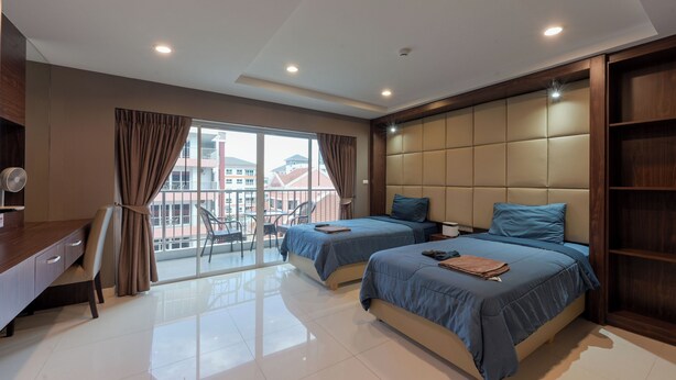 Habitación de hotel moderna con dos camas, un escritorio y un balcón con vistas a edificios.