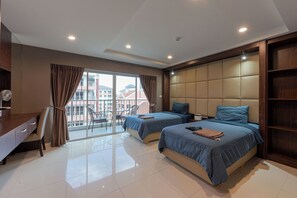 Quarto de hotel moderno com duas camas, uma escrivaninha e varanda com vista para edifícios.