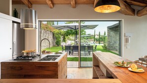 A modern kitchen with a built-in stove, a large island, and a view of an outdoor patio with a dining area.
