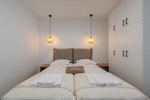 A double bed with two nightstands, a headboard, and a wardrobe with two doors.