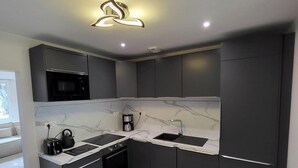Una cucina moderna con mobili scuri, un piano di lavoro in marmo e un forno a microonde integrato.