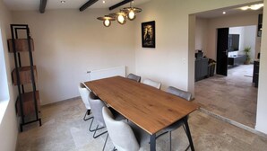 Un'area pranzo moderna con tavolo e sedie in legno, una lampada a sospensione e un termosifone sulla parete.