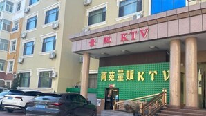 A hotel entrance with a green facade and a sign in red and yellow. - Shang Yuan Hotel (Habahe)
