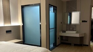 A hotel room with a bed, a bathroom with a mirror, and a sliding door. - Shang Yuan Hotel (Habahe)