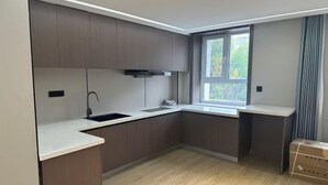 A modern kitchen with built-in cabinets, a window, and a countertop. - Shang Yuan Hotel (Habahe)