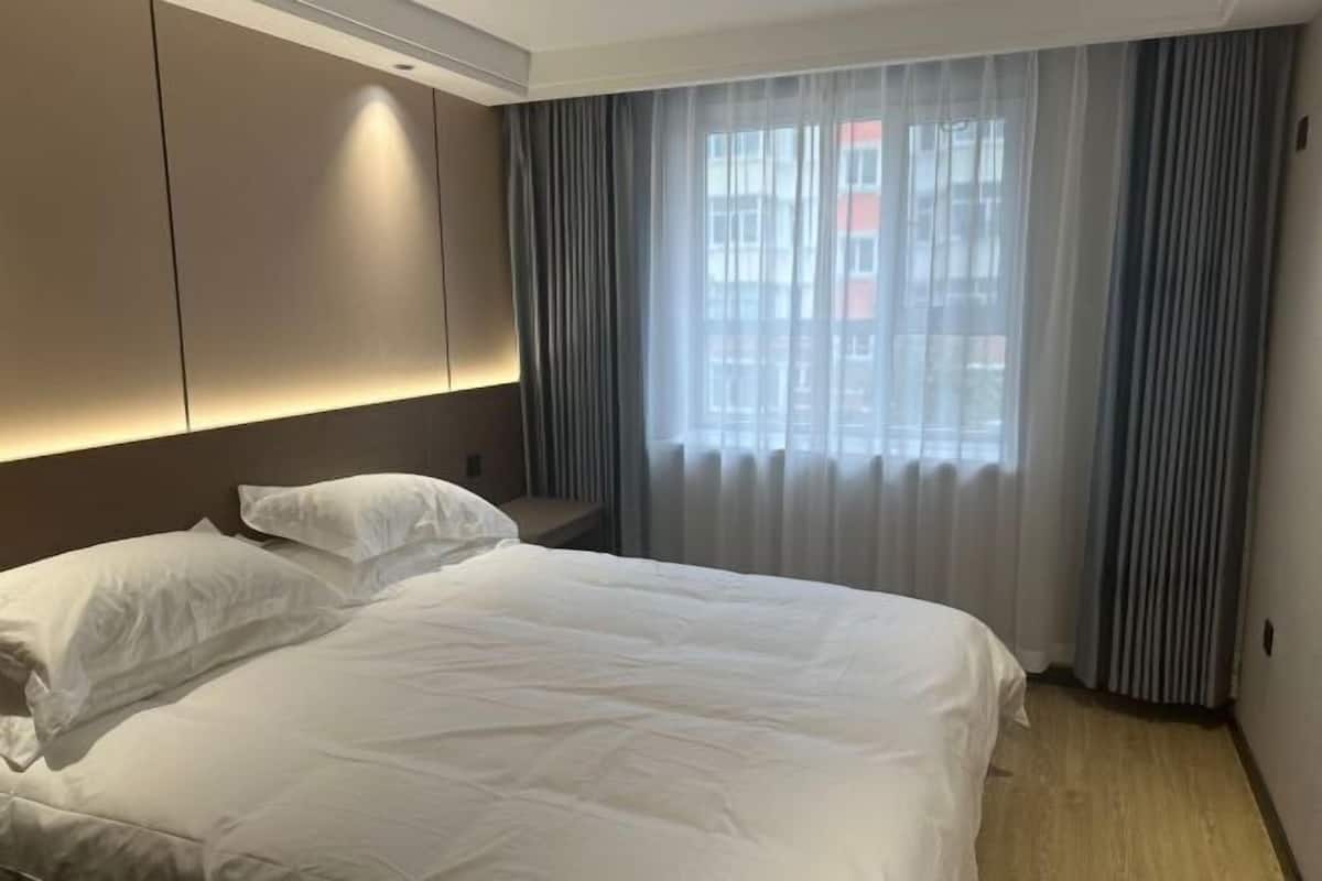 A hotel room with a bed, a nightstand, and a window with curtains.