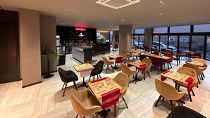 Ein modernes Café mit Tischen, Stühlen und einer Bar, mit großen Fenstern und schöner Aussicht.
