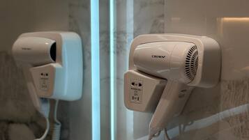 A hair dryer mounted on a wall with a mirror reflecting its image.