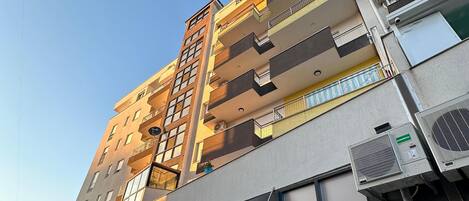 A multi-story hotel with balconies, large windows, and air conditioning units.