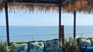 A covered outdoor seating area with a view of the ocean.