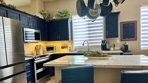A modern kitchen with dark cabinets, stainless steel appliances, a central island, and a built-in oven. - Prime Location! North Scottsdale Retreat - 1 Level Home w/Private Pool (Scottsdale)