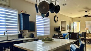 A modern kitchen with a central island, a dining area with blue chairs, and a ceiling fan. - Prime Location! North Scottsdale Retreat - 1 Level Home w/Private Pool (Scottsdale)