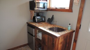 Una cocina compacta con microondas integrado, tostadora y pileta.