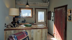 Una cocina rústica con una isla de madera, una lámpara colgante y una ventana con persianas.