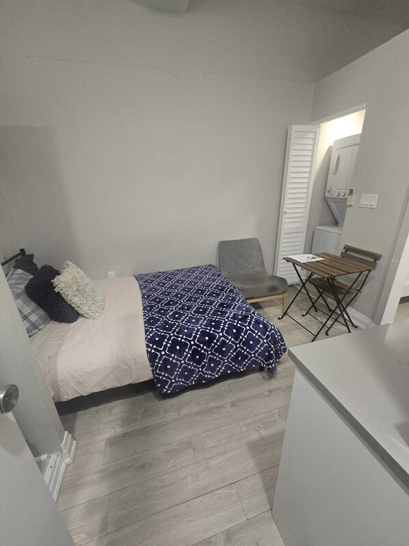A compact bedroom with a bed, a chair, and a small table.
