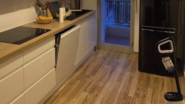 Une cuisine moderne avec des meubles blancs, un réfrigérateur noir et un plan de travail en bois.