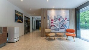A modern lobby with a reception desk, a large abstract painting, and a seating area with three chairs. - HanTing Hotel (Fuzhou Three Lanes And Seven Alleys) (Fuzhou)