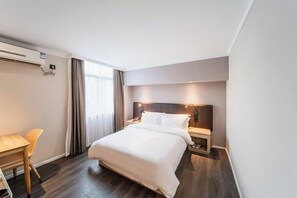 Une chambre d’hôtel comprenant un lit, une table de chevet, une lampe et un bureau avec une chaise.