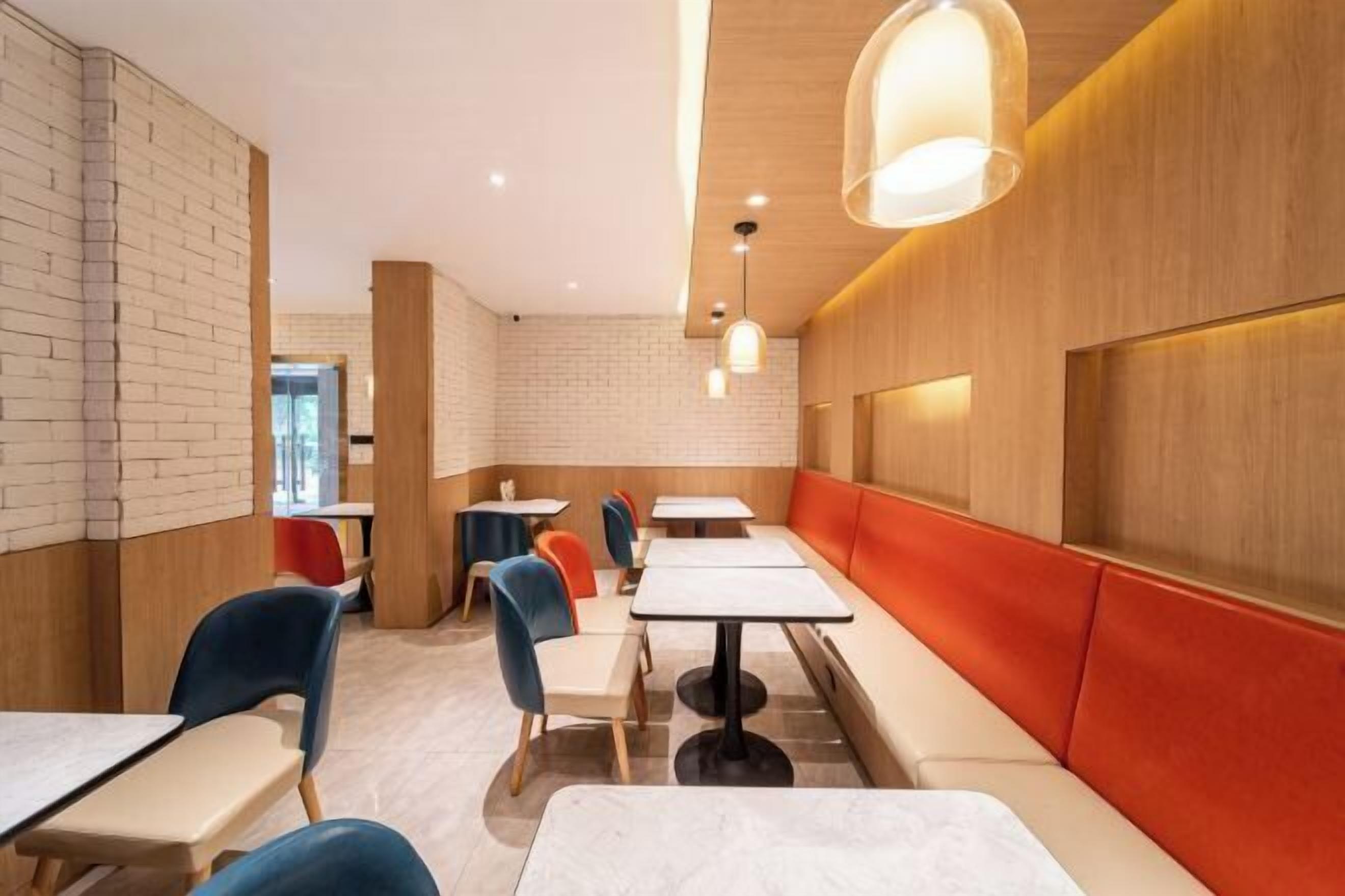 Un restaurant moderne avec un intérieur caractérisé par des murs en briques, des lambris en bois et une variété de types de sièges, notamment des tables et des banquettes.