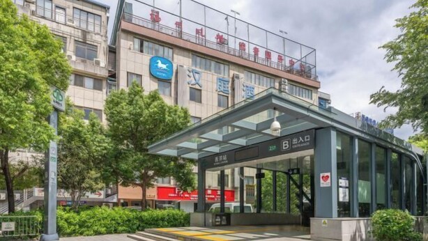 A hotel entrance with a glass canopy, a sign indicating the entrance, and a visible staircase leading up to the entrance. - HanTing Hotel (Fuzhou Three Lanes And Seven Alleys) (Fuzhou)