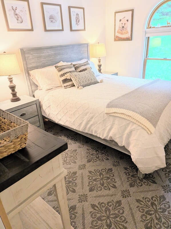 A neatly made bed with patterned bedding, a bedside table with a lamp, and framed artwork on the wall. - Charming 3BR house, nestled in mountains, pet friendly, 20 minutes from skiing! (Stamford)