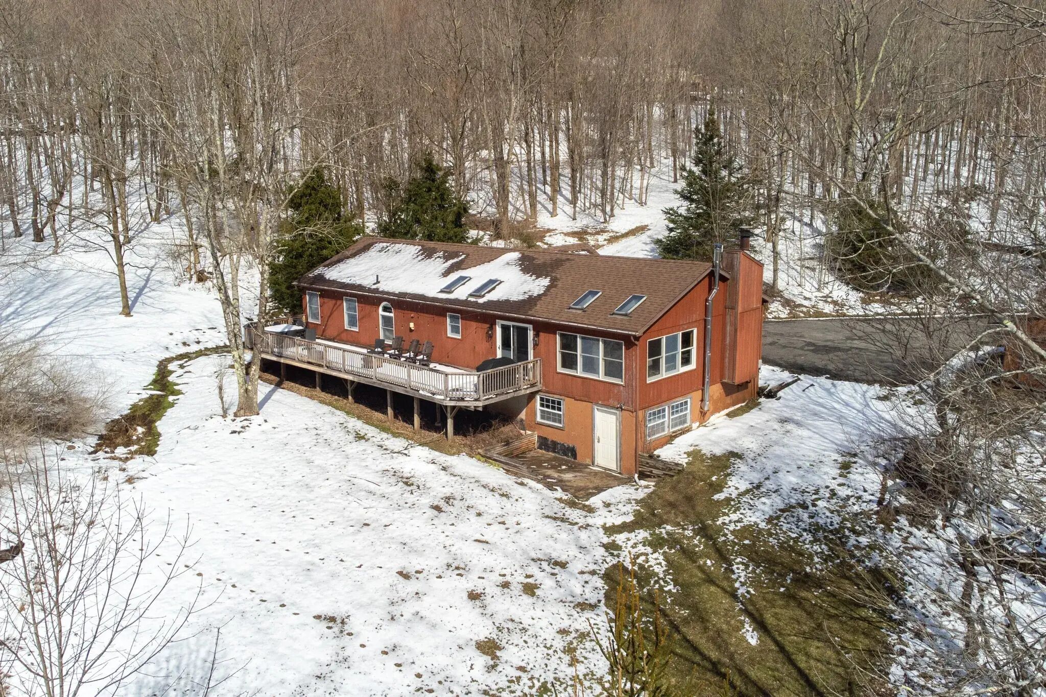 A two-story house with a balcony, surrounded by a snowy landscape and trees.
