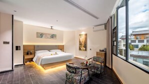 A modern hotel room with a large bed, two chairs, a small table, and a large window offering a city view. - Lijiang Yueyou International Hotel (Lijiang Old Town Branch (Lijiang)