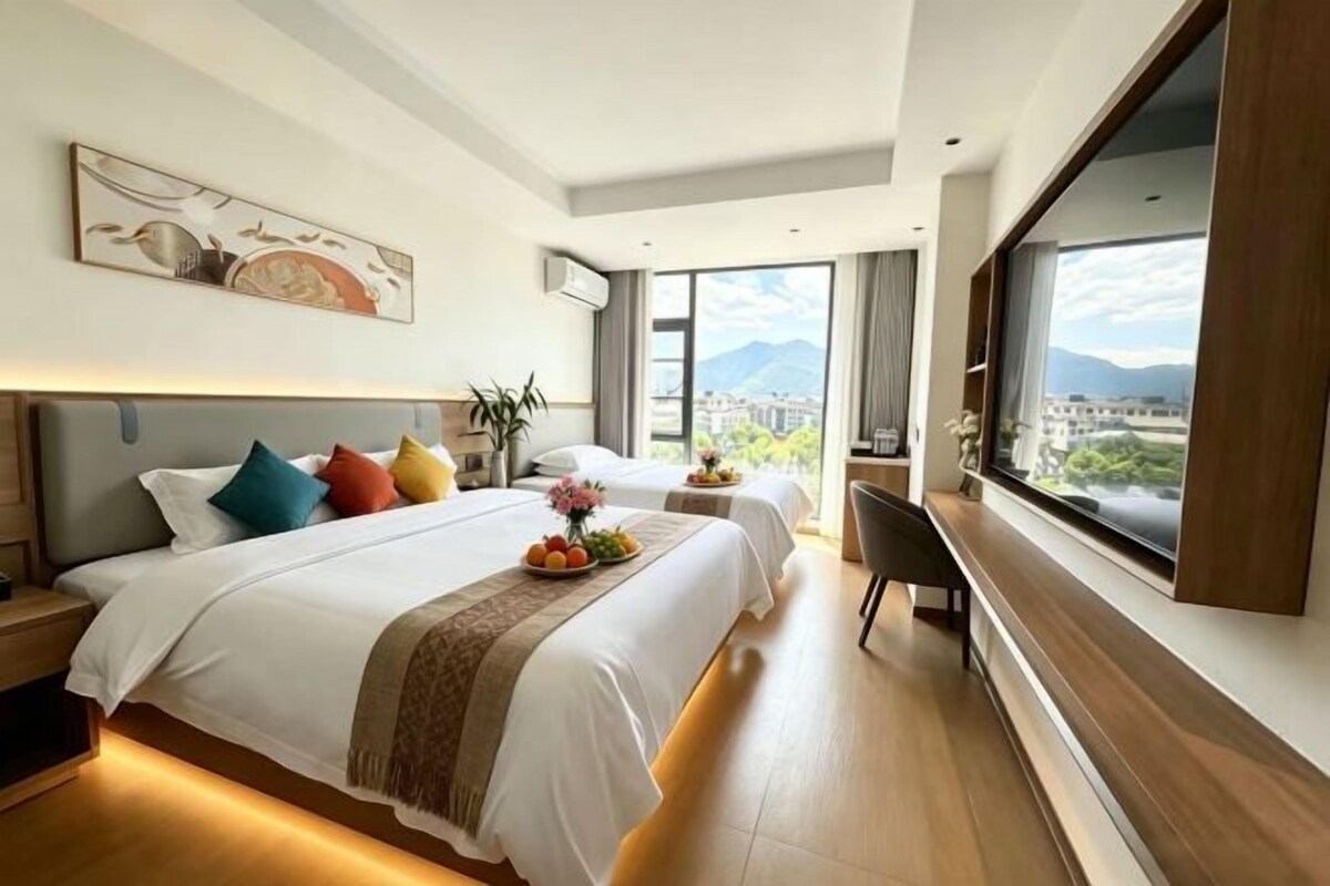 Une chambre d’hôtel avec deux lits, une grande fenêtre et une vue sur la ville.