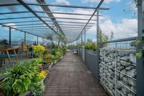 A covered walkway with potted plants, a seating area, and a view of the sky. - Lijiang Yueyou International Hotel (Lijiang Old Town Branch (Lijiang)