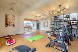 A spacious gym with exercise equipment, yoga mats, and a view of the outdoors. - Lijiang Yueyou International Hotel (Lijiang Old Town Branch (Lijiang)