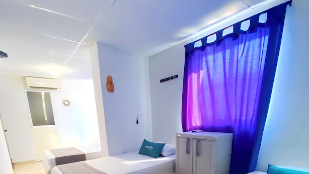 A modern hotel room with two beds, a wardrobe, and a small kitchenette. - Hotel Puerto Vigia Inn (Cartagena)
