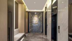 Elevador moderno com parede de mármore e emblema dourado.