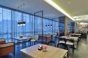 A modern dining area with tables and chairs, large windows, and pendant lighting. - Orange Hotel (Suzhou Dushu Lake Xi'an Jiaotong-Liverpool University) (Suzhou)