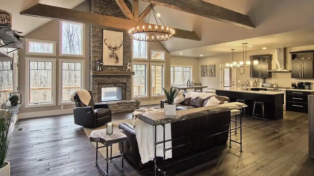 A spacious living area with a fireplace, a large window, and a kitchen with a bar. - Beautiful Mountain Home, Ski In/Ski Out & Golf within Boyne Mountain Resort (Boyne falls)