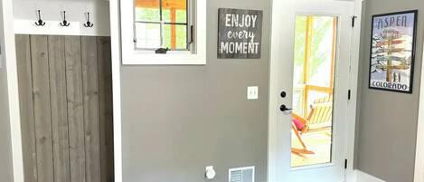 Un couloir avec une porte en bois, une petite fenêtre et une affiche aux messages inspirants.