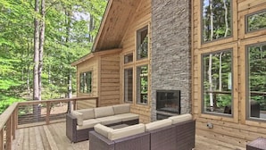 A wooden cabin with a stone fireplace, large windows, and outdoor seating. - Beautiful Mountain Home, Ski In/Ski Out & Golf within Boyne Mountain Resort (Boyne falls)
