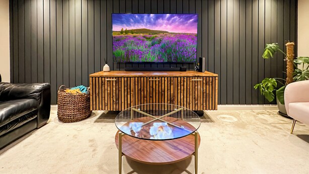 A modern living room with a flat-screen TV on a wooden console, a glass coffee table, a black leather sofa, and a potted plant. - Sheffield Charming Detached 4bd Home (Catcliffe)