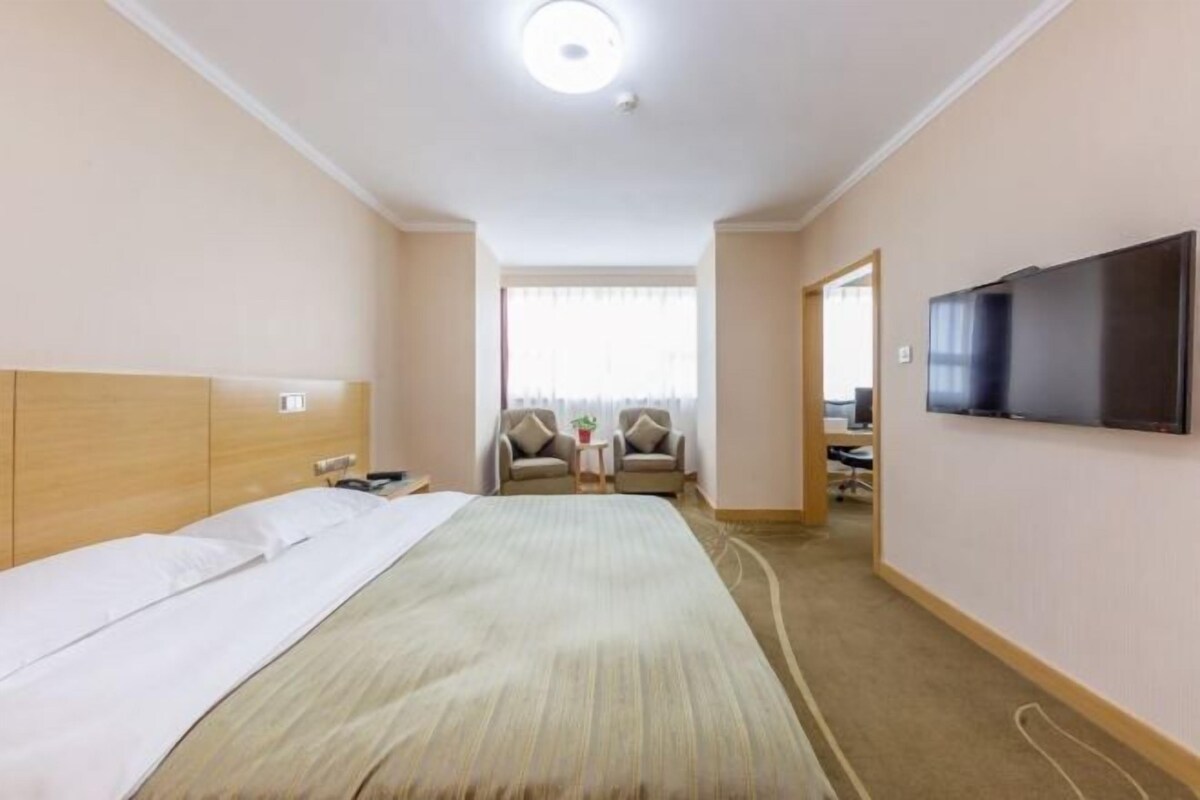 Une chambre d’hôtel avec un lit, une télévision, un bureau et une chaise.